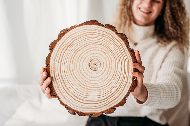 Lisa Turcanu hält eine Baumscheibe mit sichtbaren Jahresringen.